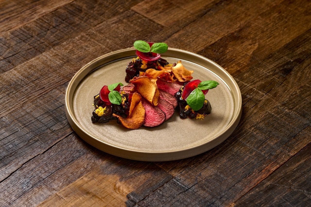 A plate of food with meat and vegetables on a wooden table.