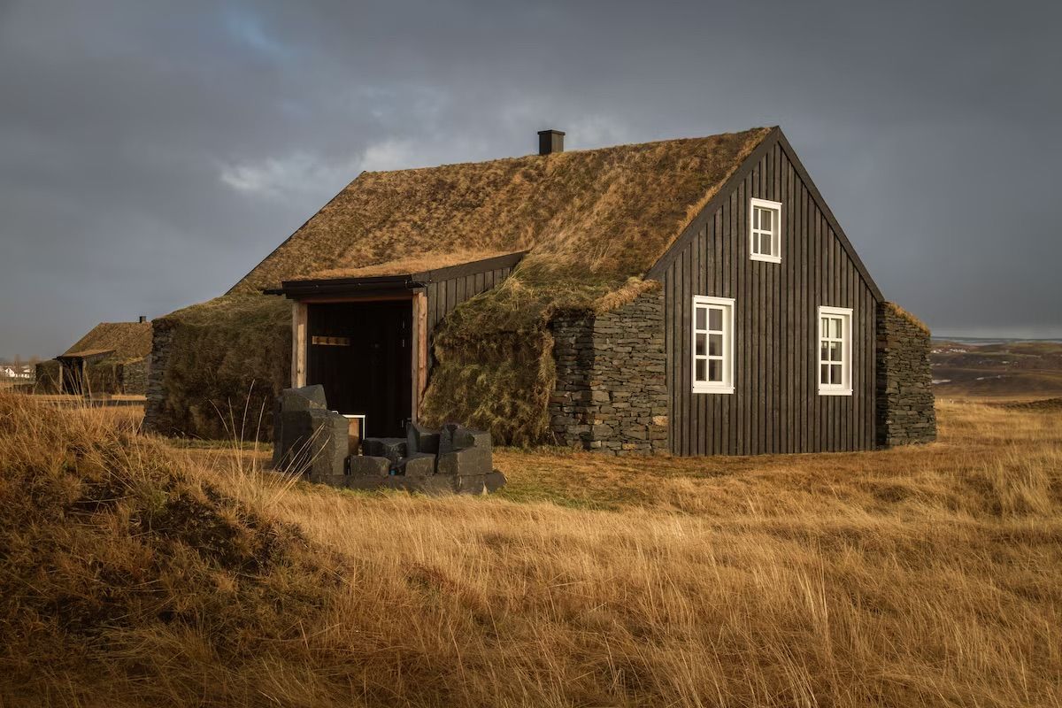A small house is sitting in the middle of a field.
