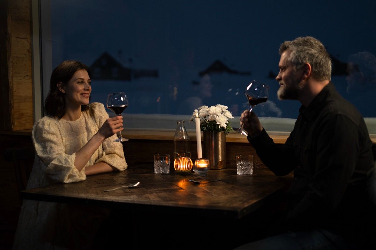 A man and a woman are sitting at a table in front of a window.