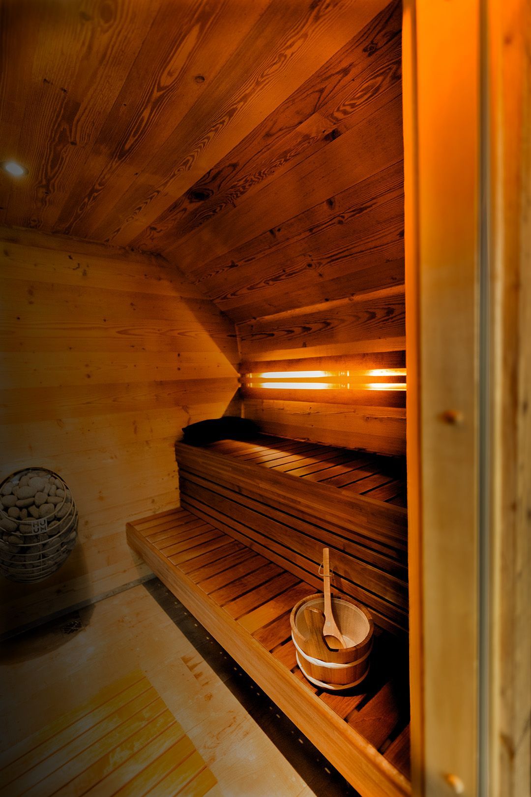 A wooden sauna with a bucket and a spoon in it.