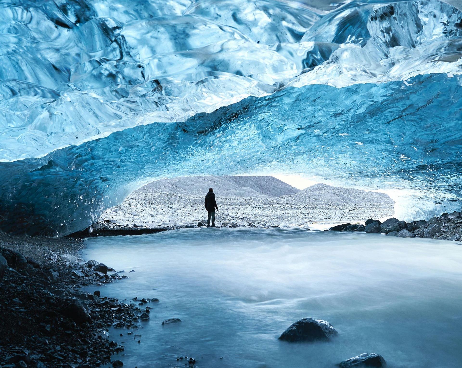 A man is standing in the middle of an ice cave.