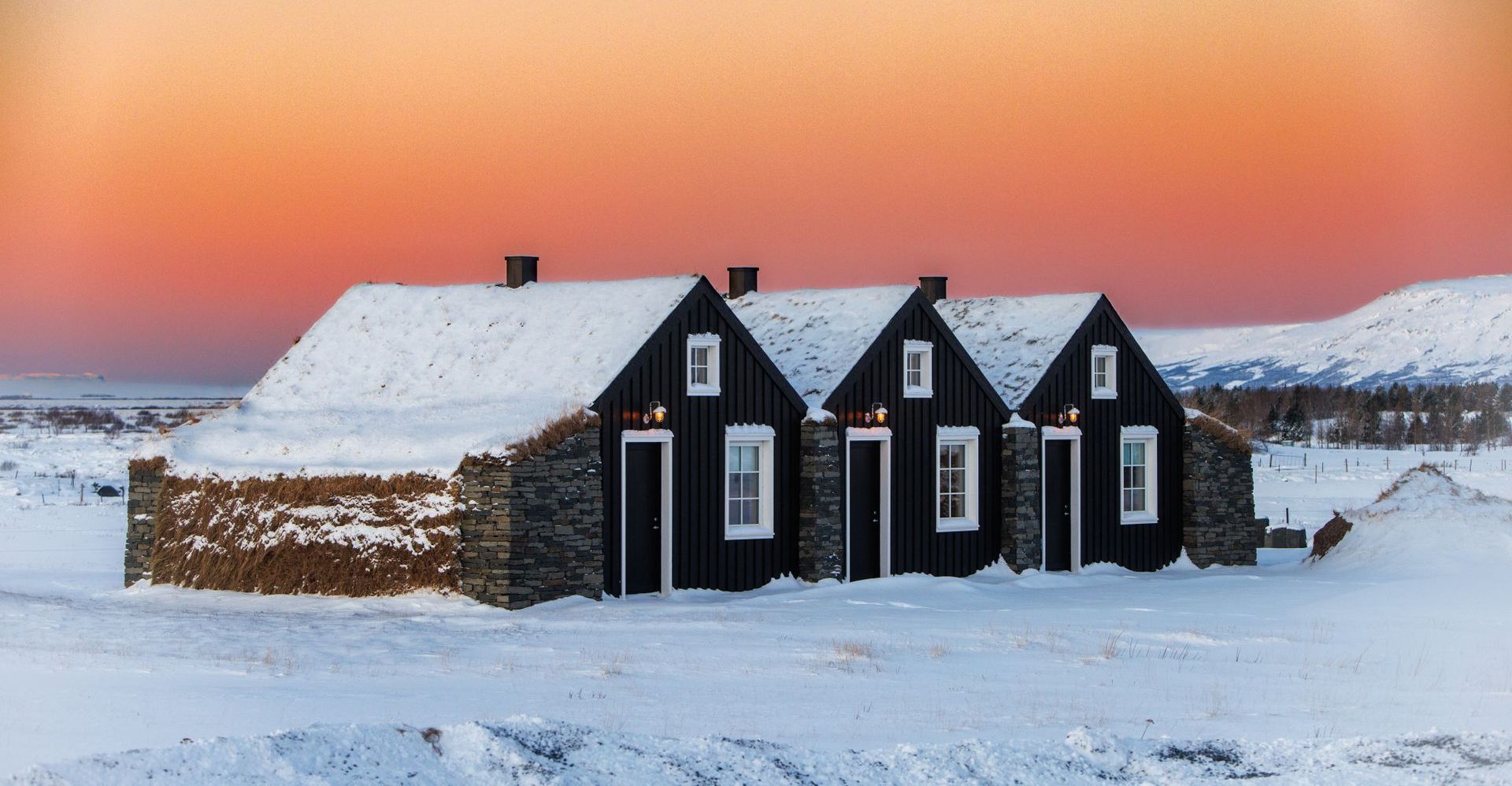 A row of houses covered in snow with a sunset in the background.