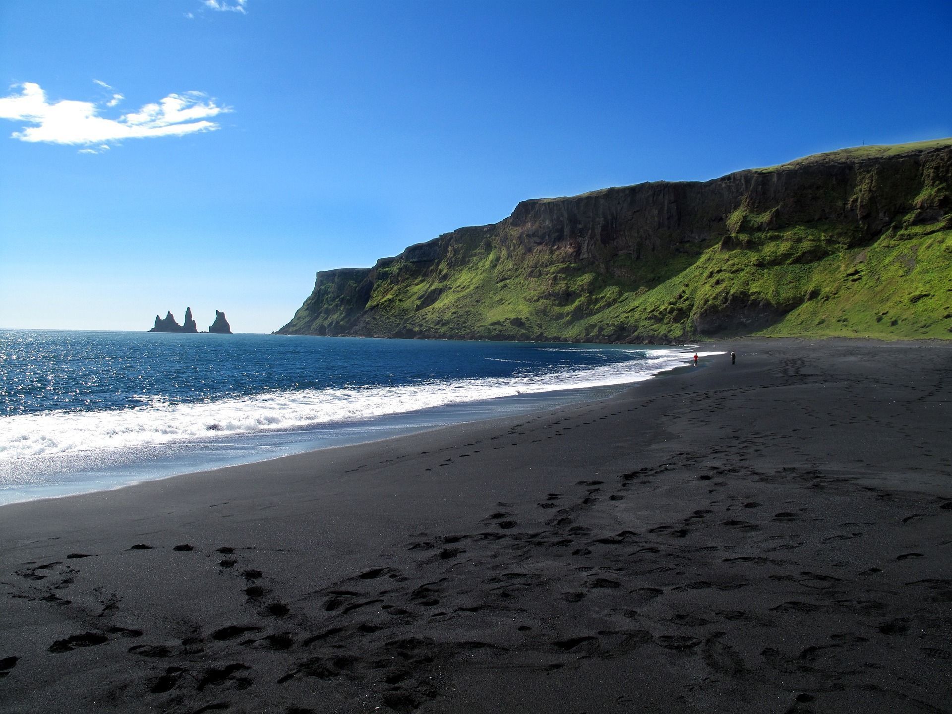 A black sandy beach with a mountain in the background