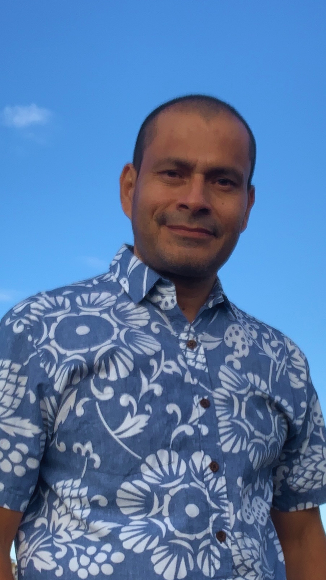 A man wearing a blue shirt with white flowers on it