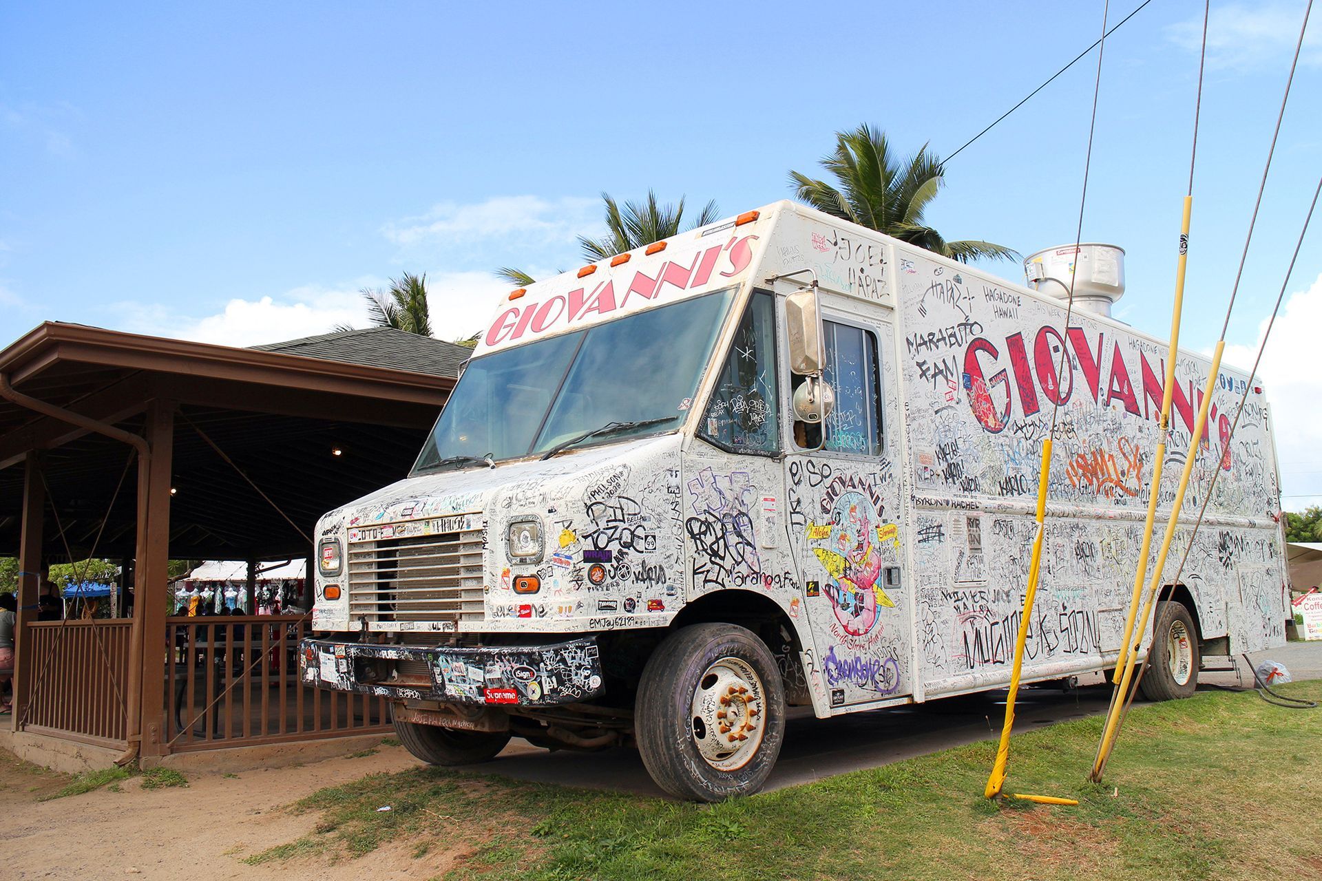 A white food truck with graffiti on it is parked in front of a building.