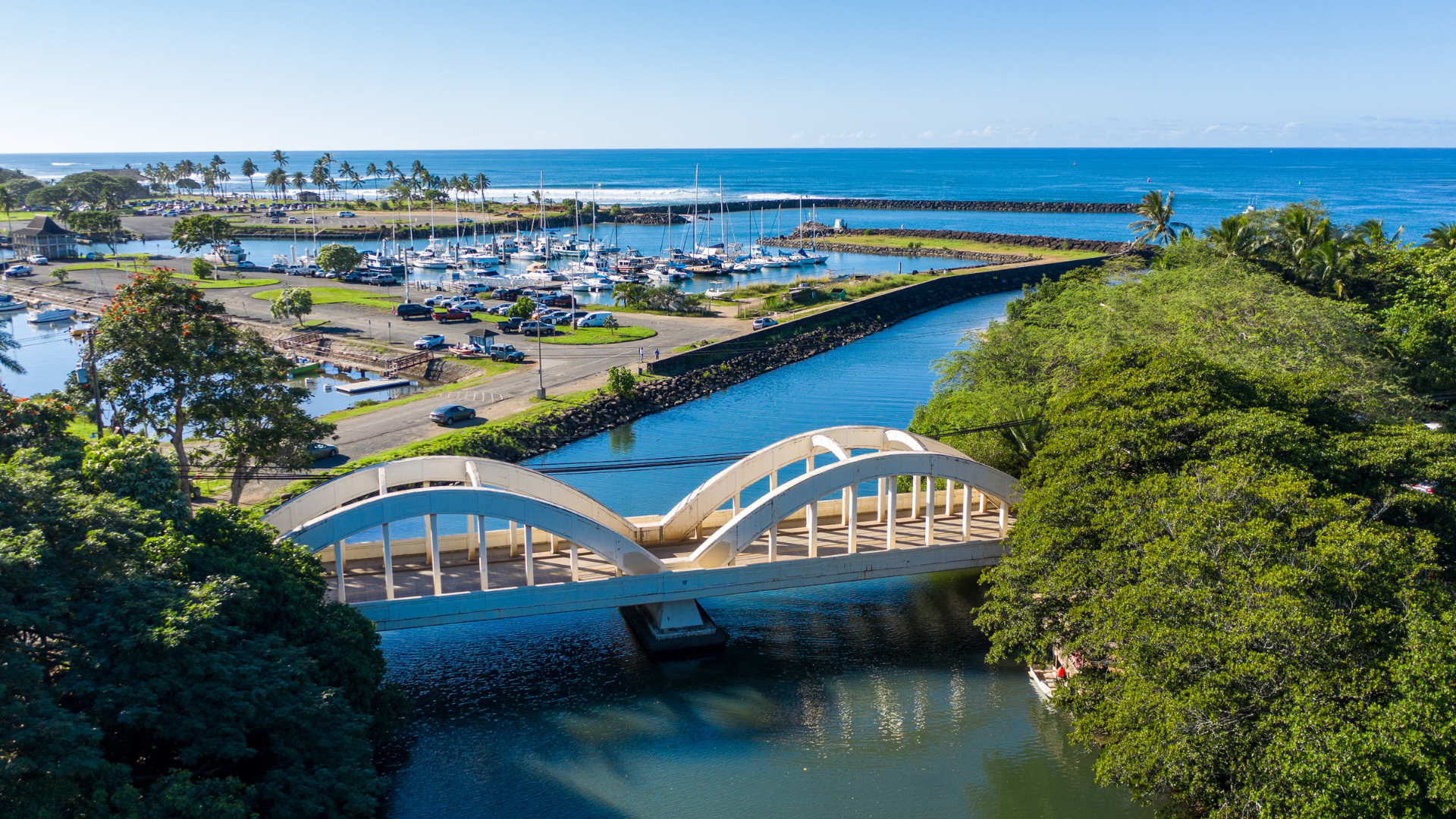 An aerial view of a bridge over a river leading to the ocean.