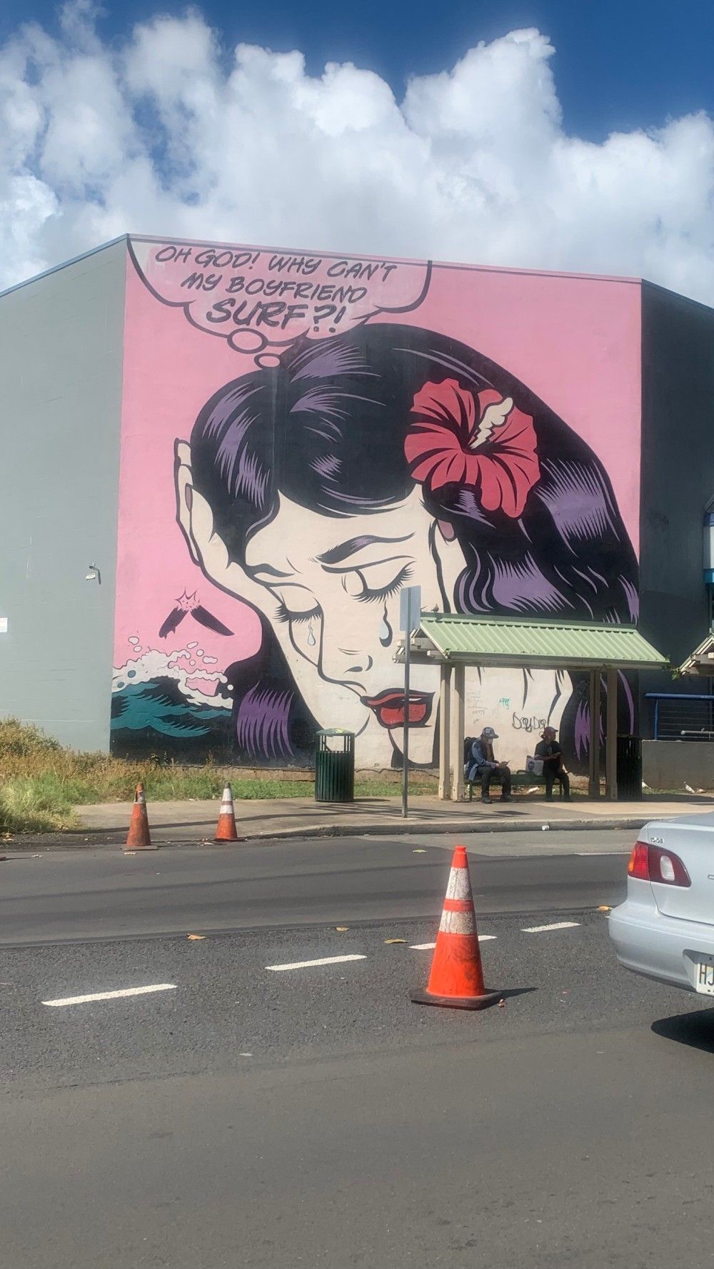 A large mural of a woman with a flower in her hair is on the side of a building.