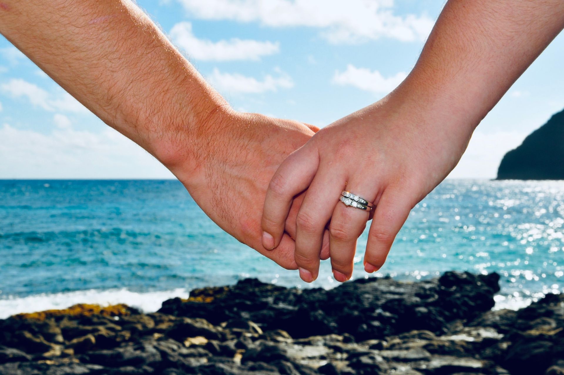 A couple holding hands with the words love on the lava rocks below them