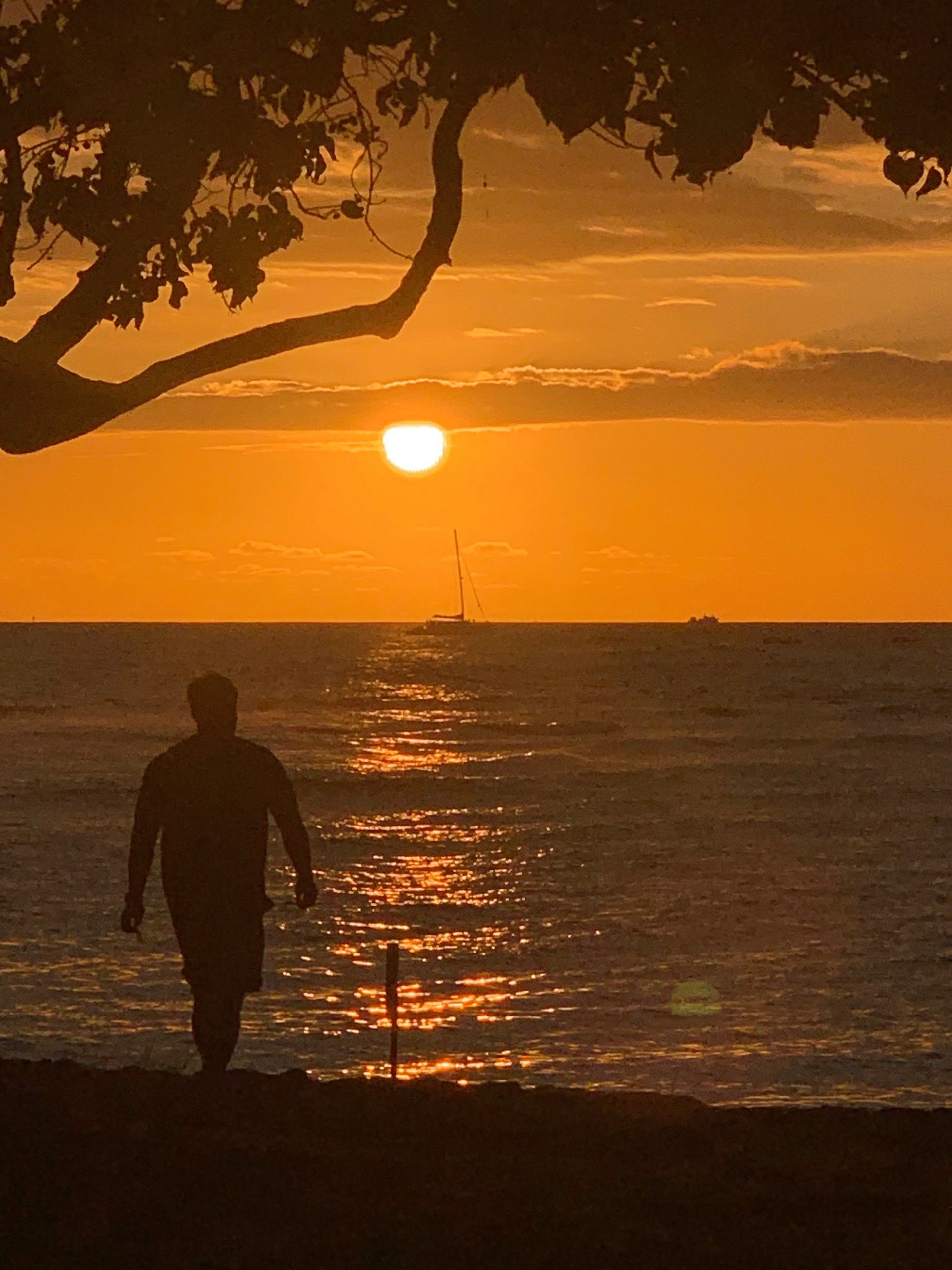 A man is walking on the beach at sunset