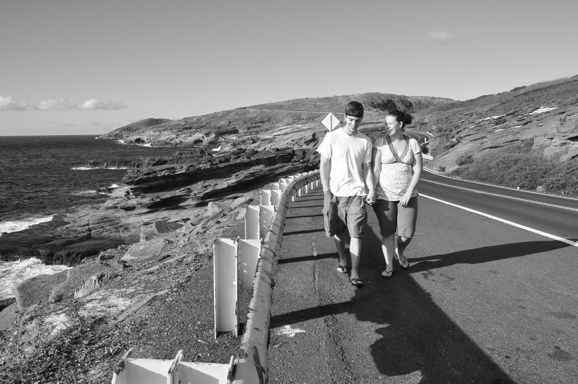 Couple walking at the road near the ocean