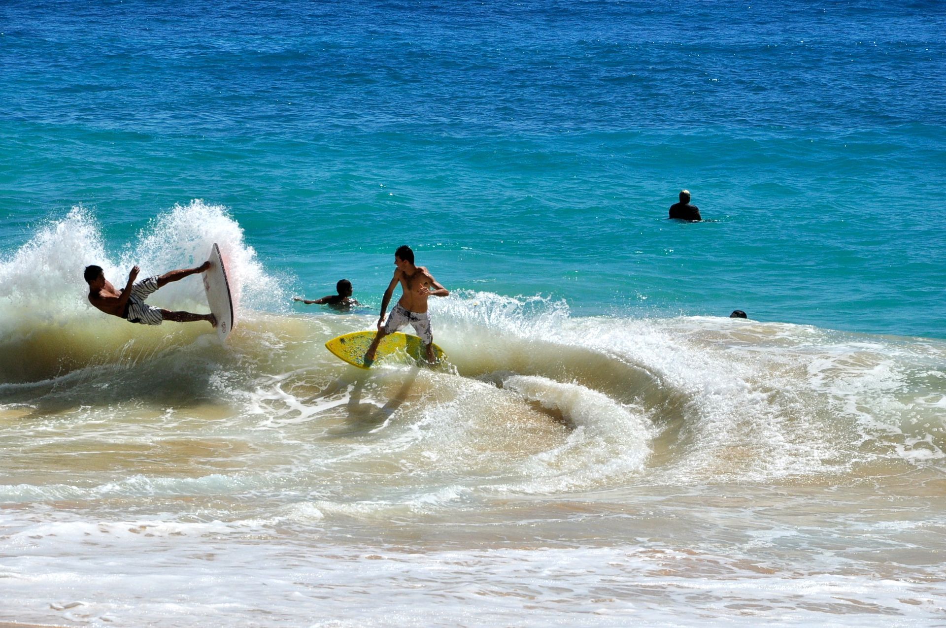 An aerial view of a person riding a wave on a surfboard in the ocean.