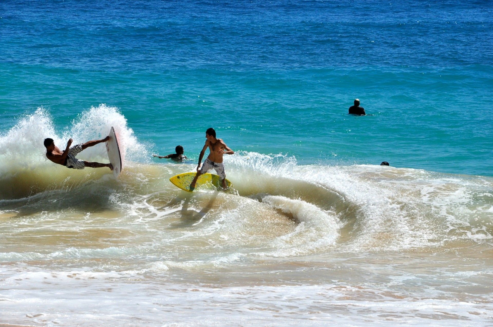 Two surfers are riding a wave on a beach