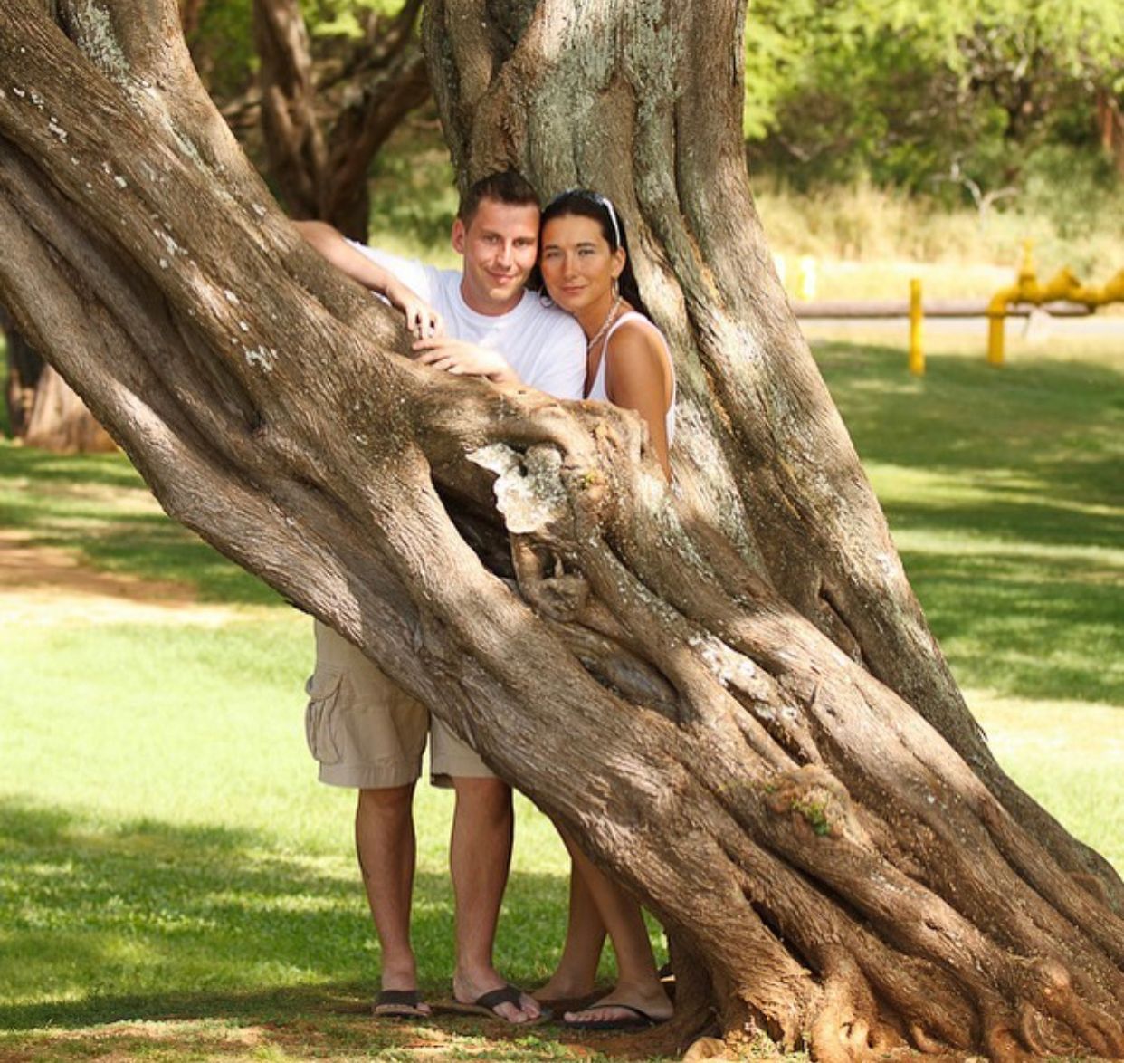 A man and a woman standing next to a tree
