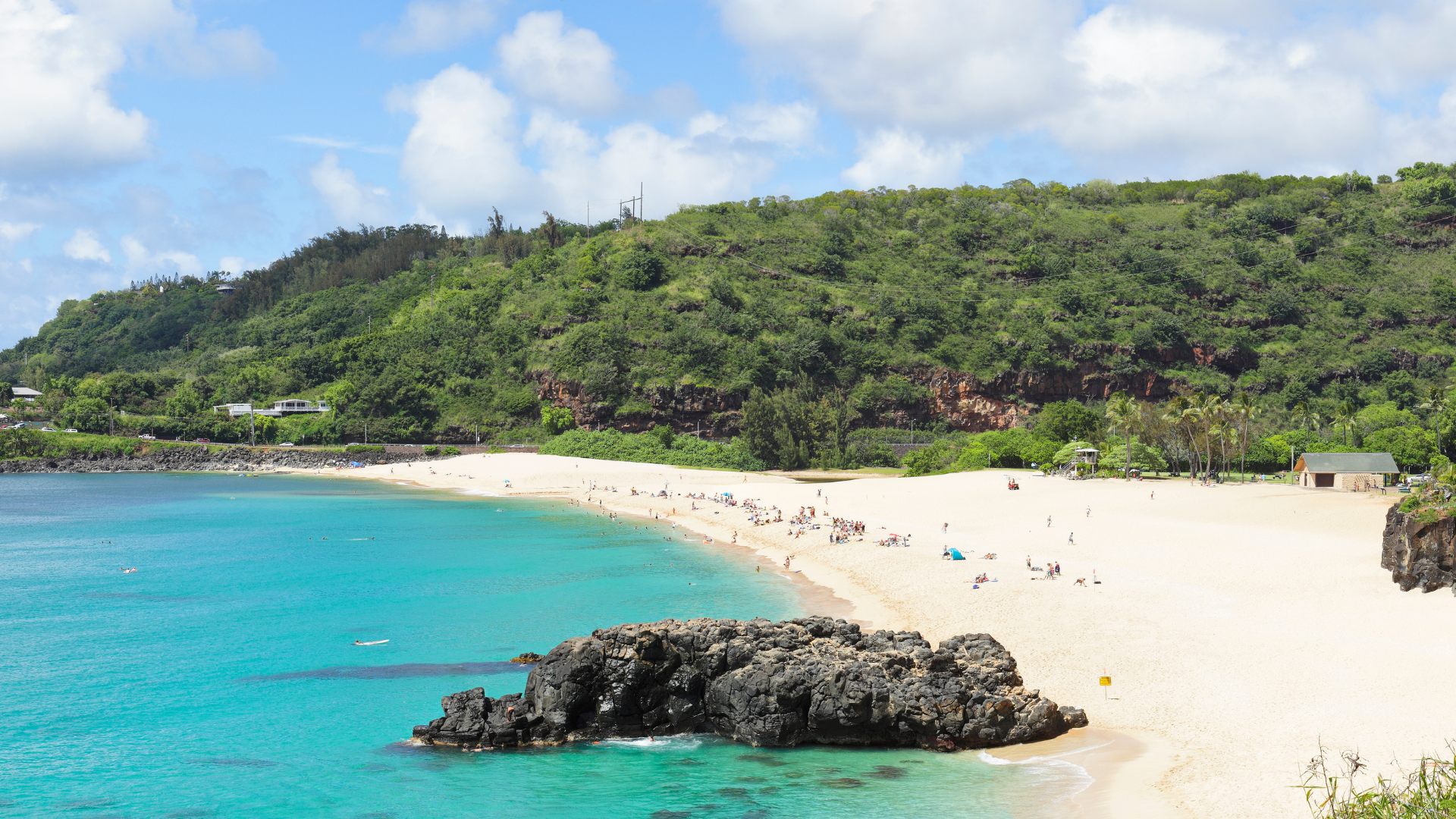 A beach with a lot of people on it and a mountain in the background