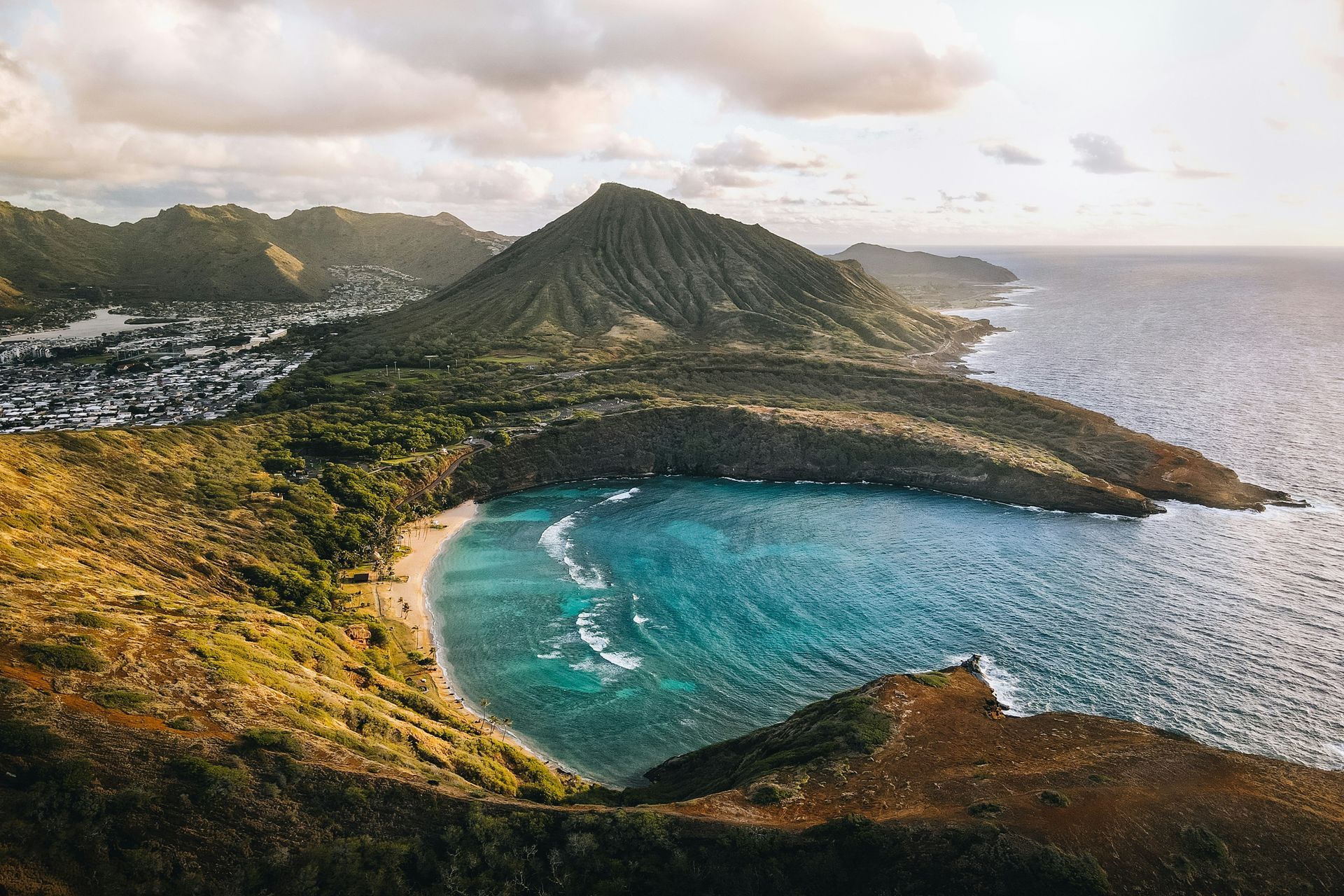 An aerial view of a beach surrounded by mountains and a body of water.