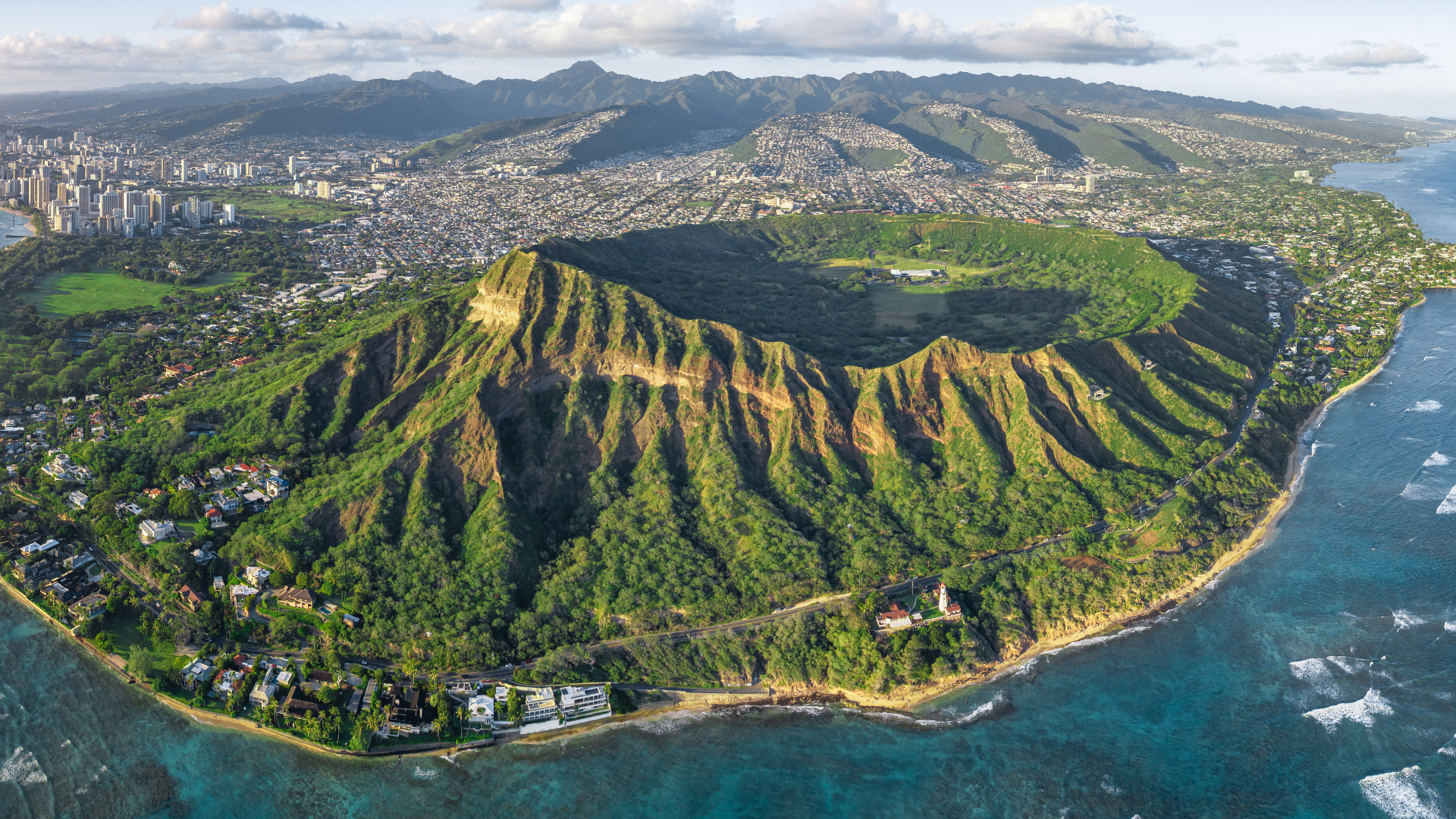 An aerial view of a small island in the middle of the ocean surrounded by mountains.