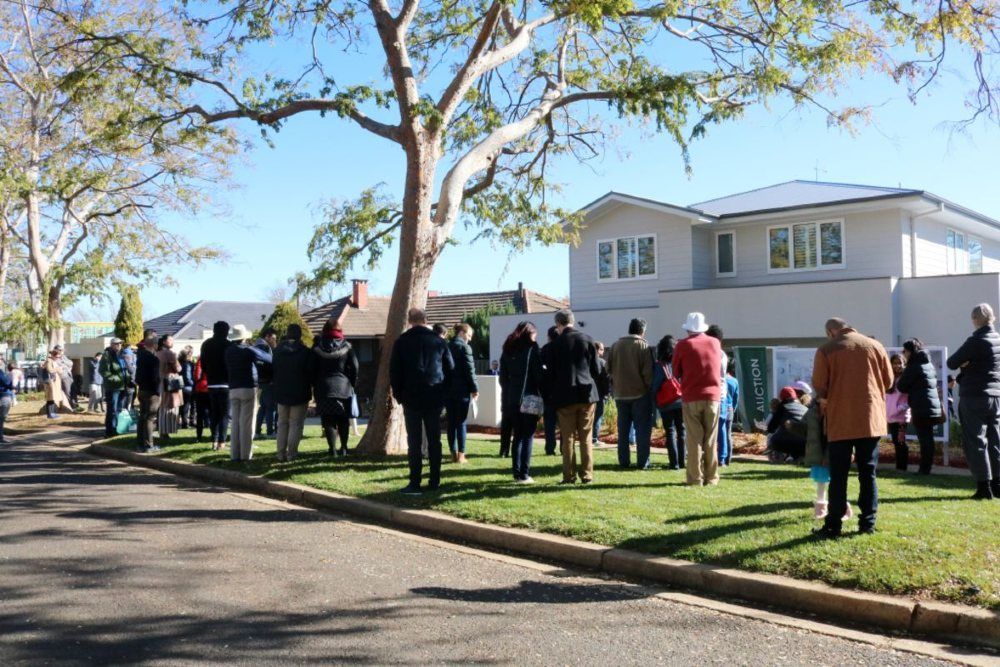 People gathered outside a house, waiting for a real estate auction to begin