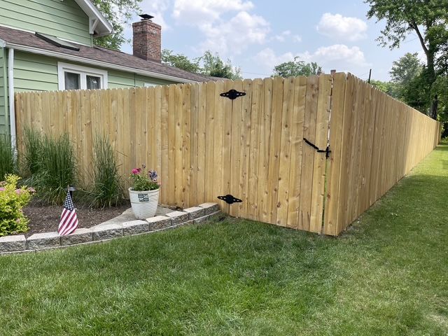 A wooden fence with a gate in the backyard of a house.