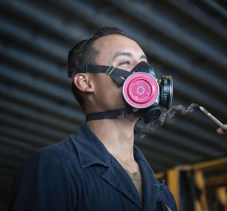 A man wearing a respirator mask is being fit tested using a Nextteq® VeriFit® Irritant Smoke Generator.