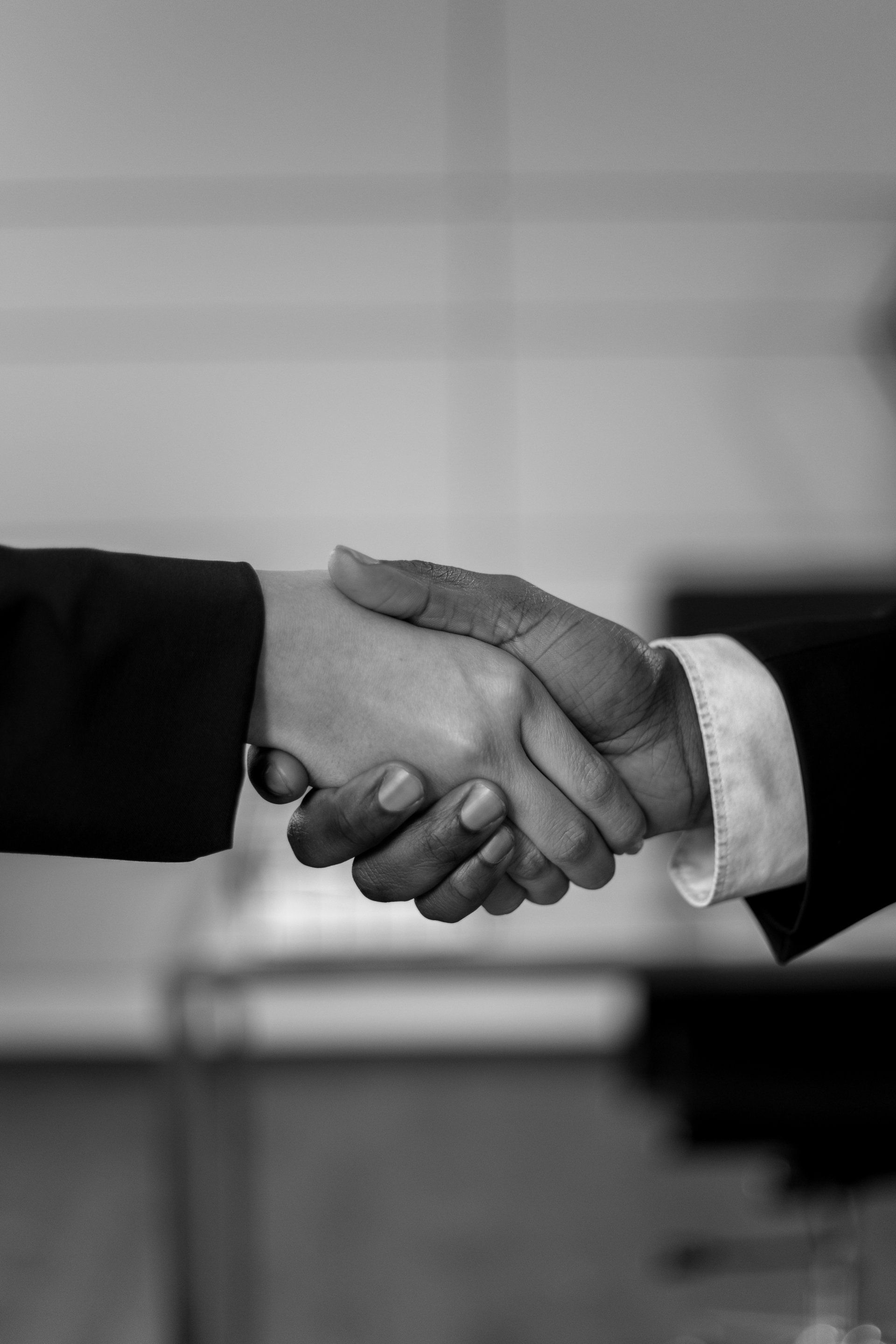 Two people are shaking hands in a black and white photo.