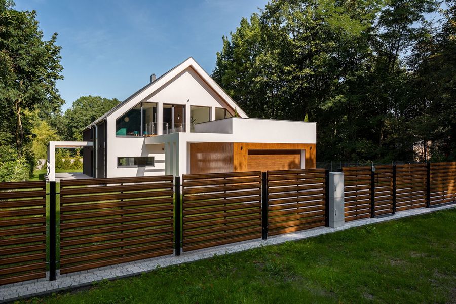 A modern house with a wooden fence in front of it.