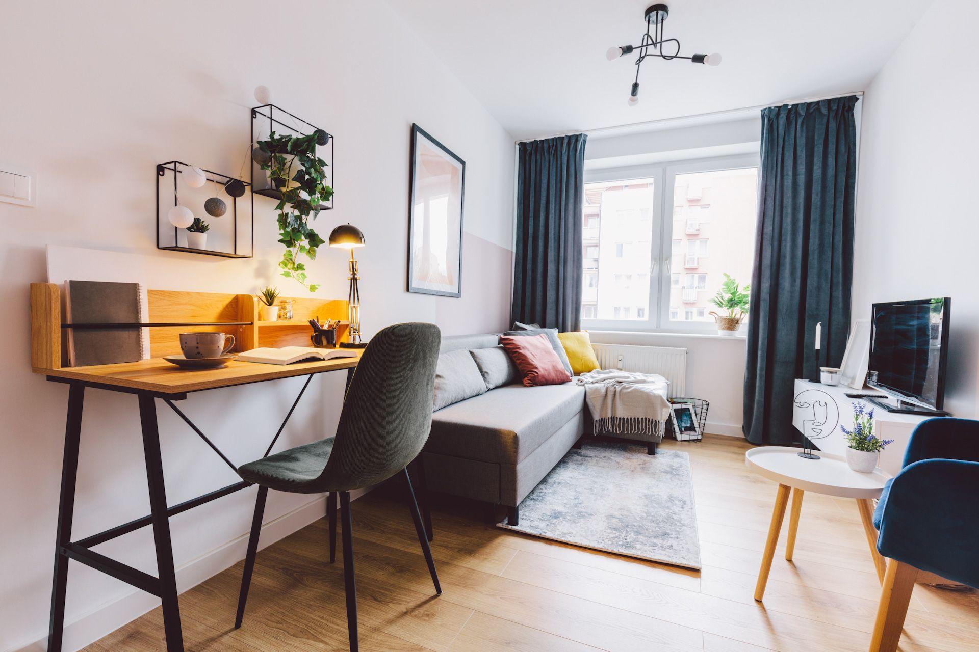 A living room with a couch , desk , chair and television.