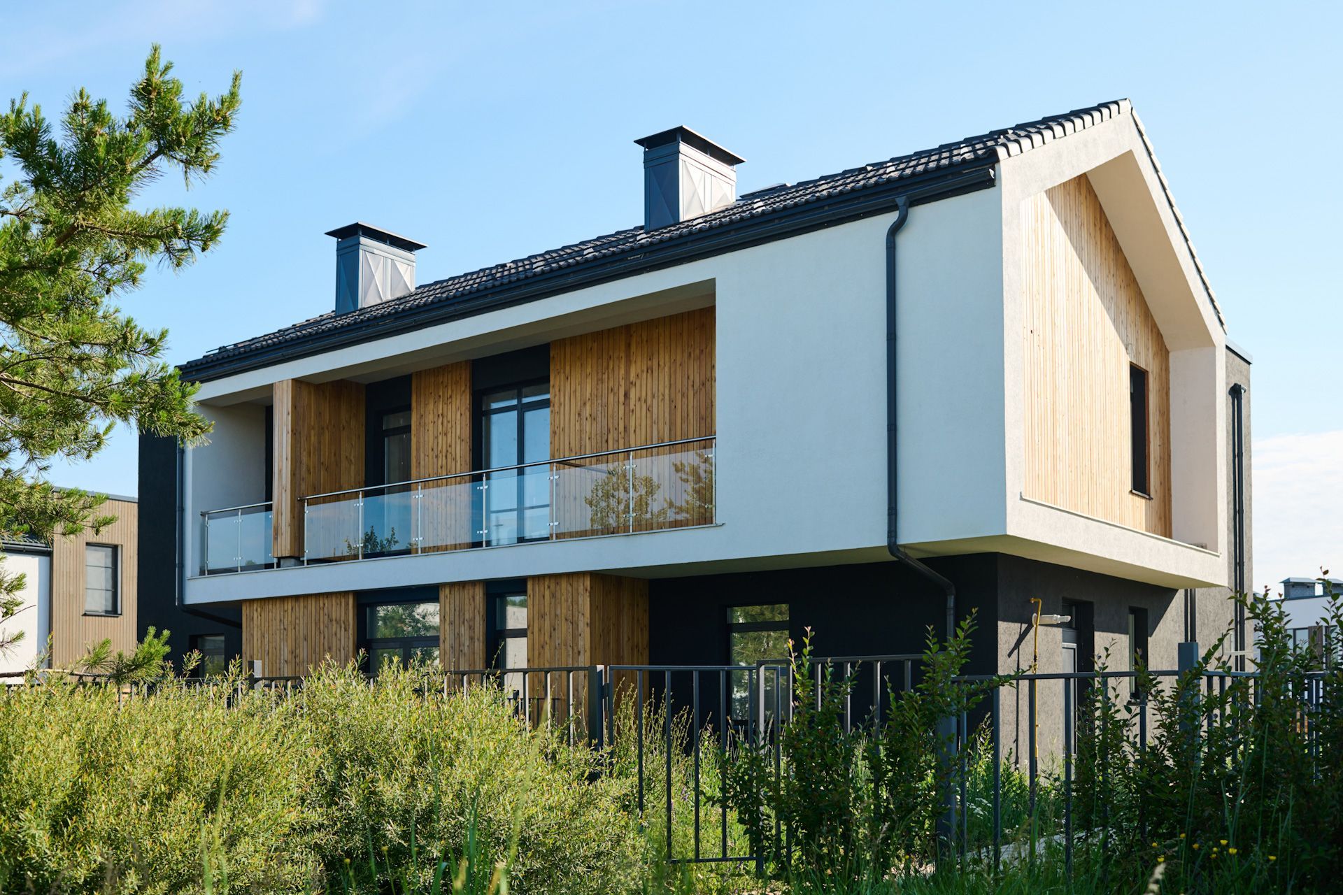 A modern house with a balcony and a fence in front of it.
