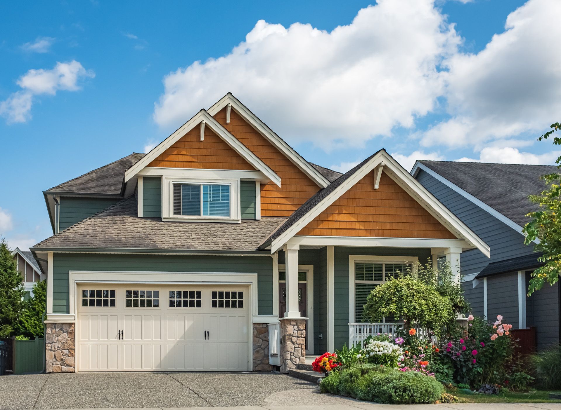 A large house with a large garage and a blue sky in the background.