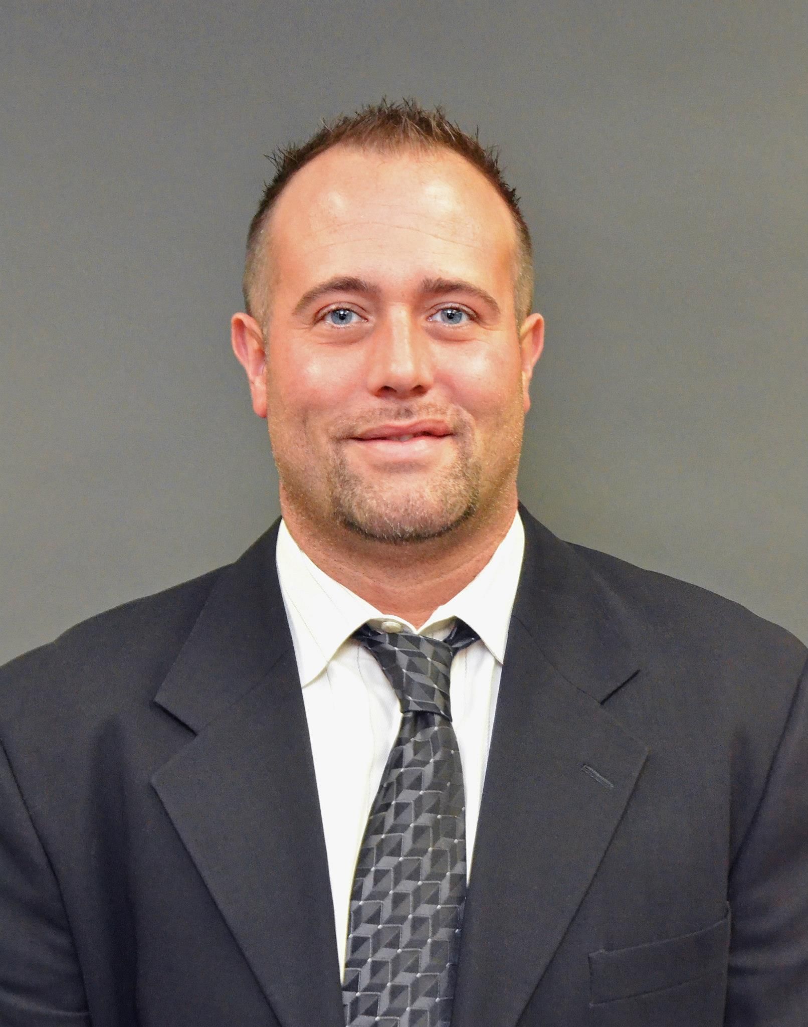 A man is holding a dog in his arms and the dog is wearing a sweater.