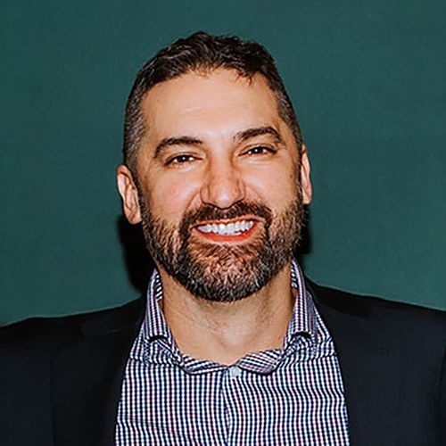 A man and a woman are sitting on a dock overlooking a lake.