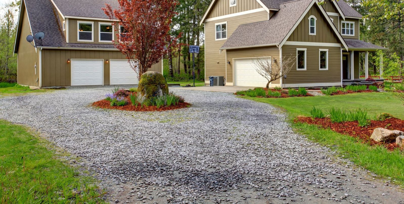 A large house with a gravel driveway in front of it.