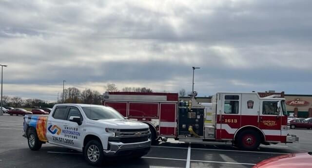 Unified Restoration Systems truck parked next to an Akron Firetruck at an Acme parking lot. URS helps home and businesses mitigate and restore damages from fire, flood, storms, and mold! (234) 571-2005