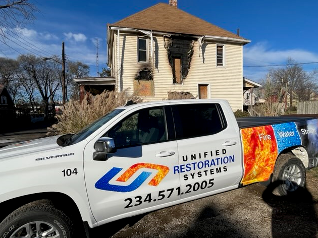 Fire damage in a bedroom, with Unified Restoration Systesm Truck