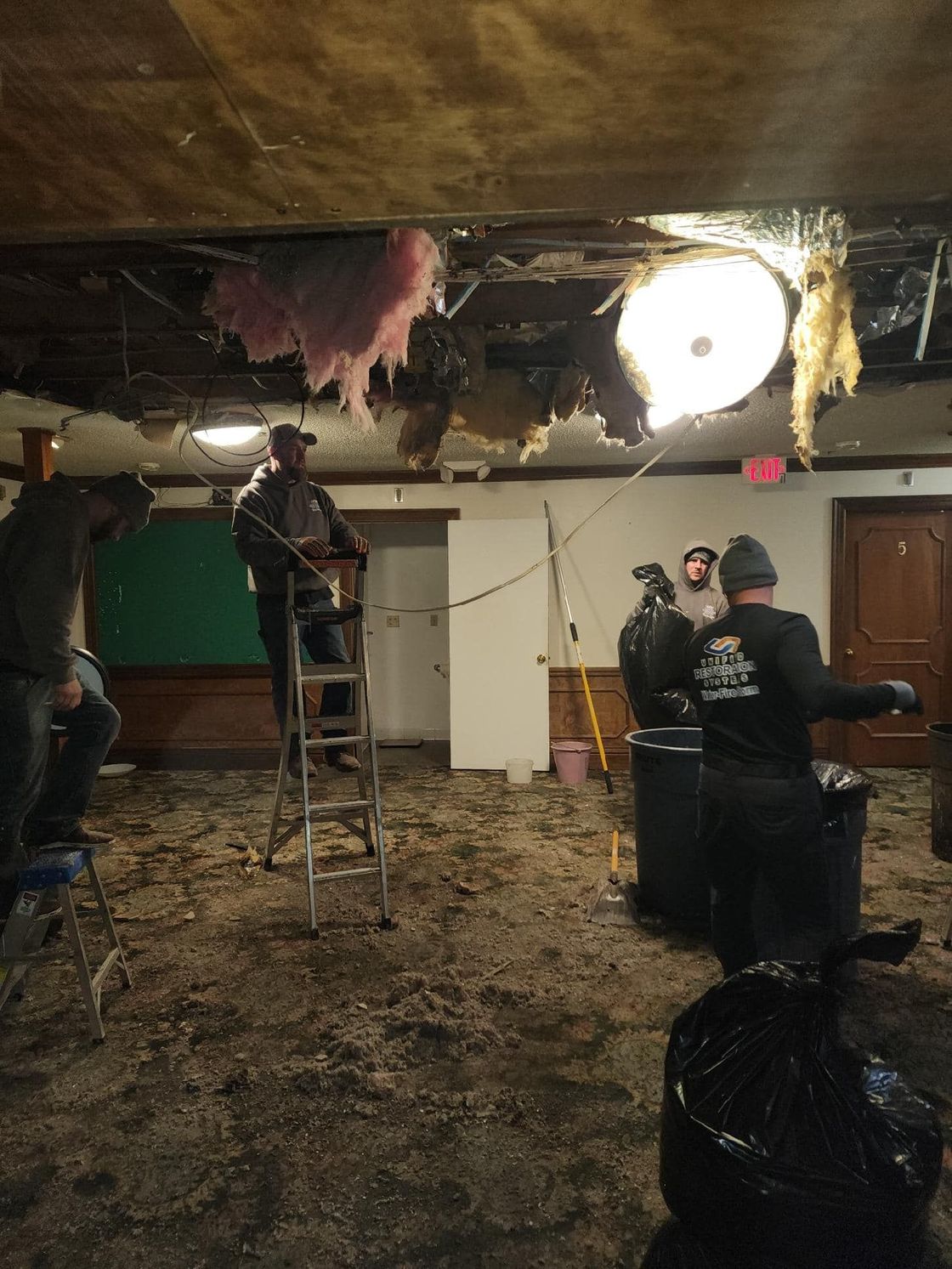 Unified Restoration Systems crew in a basement that suffered severe water damage.  The carpet was ripped out and much of the ceiling