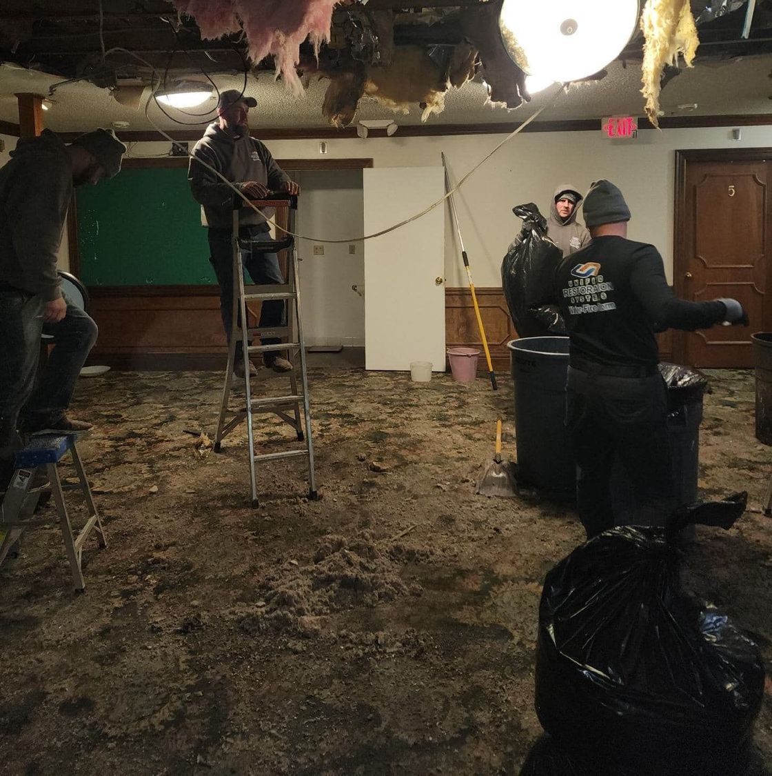 Unified Restoration Systems crew in a basement that suffered severe water damage.  The carpet was ripped out and much of the ceiling