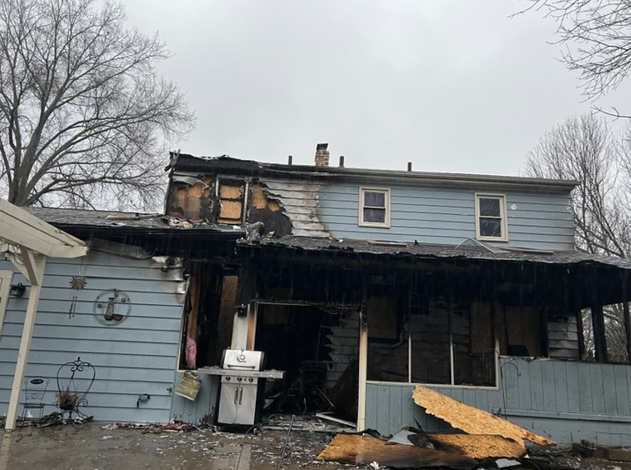Rear view of a boarded up home that sustained heavy fire damages