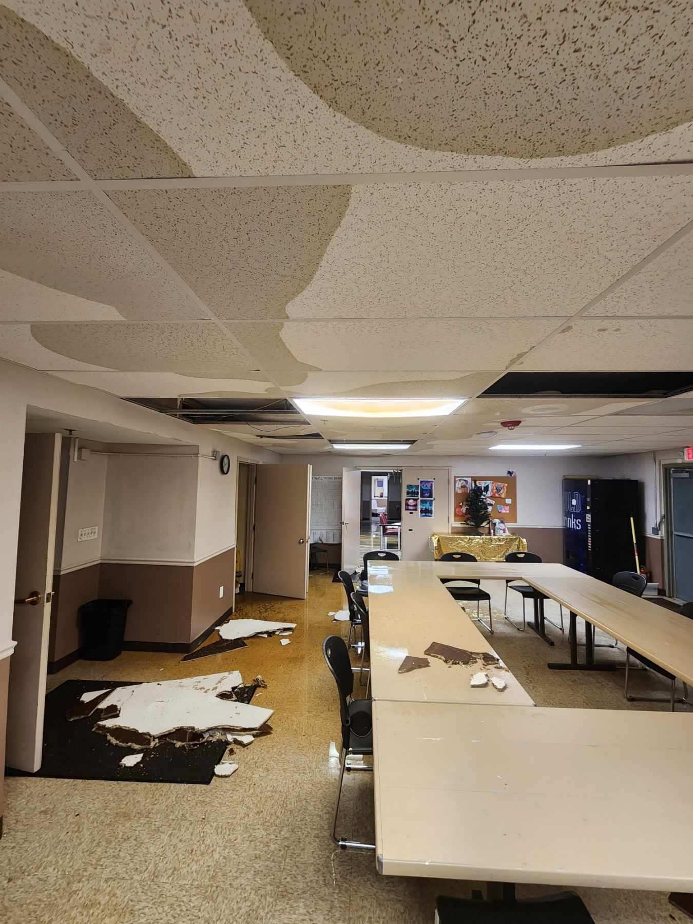 A business with flooding in the ceiling, water and paneling are all over the floor