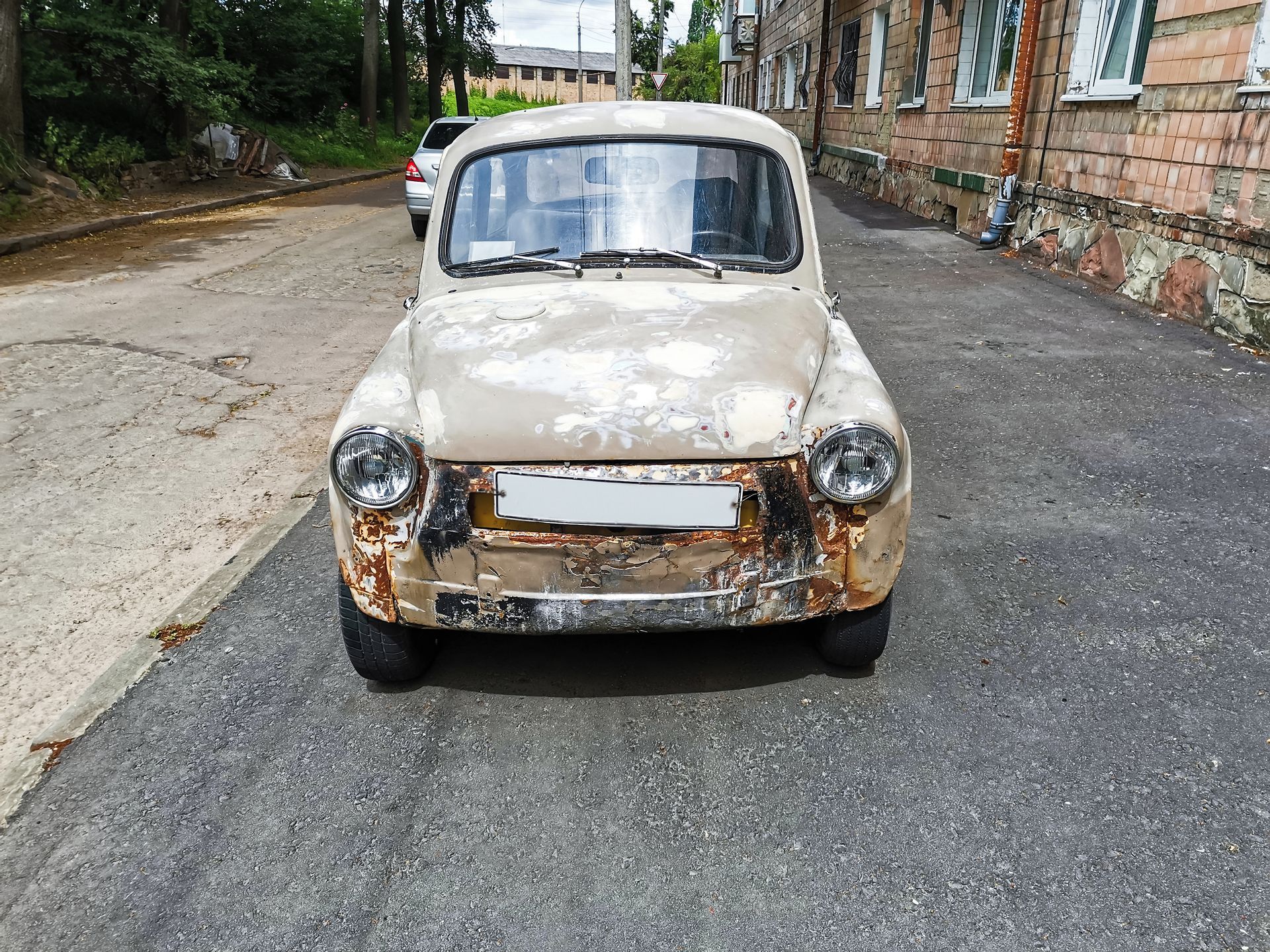 Antique broken car parked on city street front view. Antique broken car parked on city street front view.