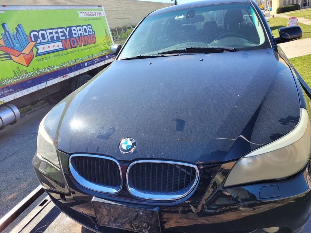 A black bmw is sitting on top of a tow truck.