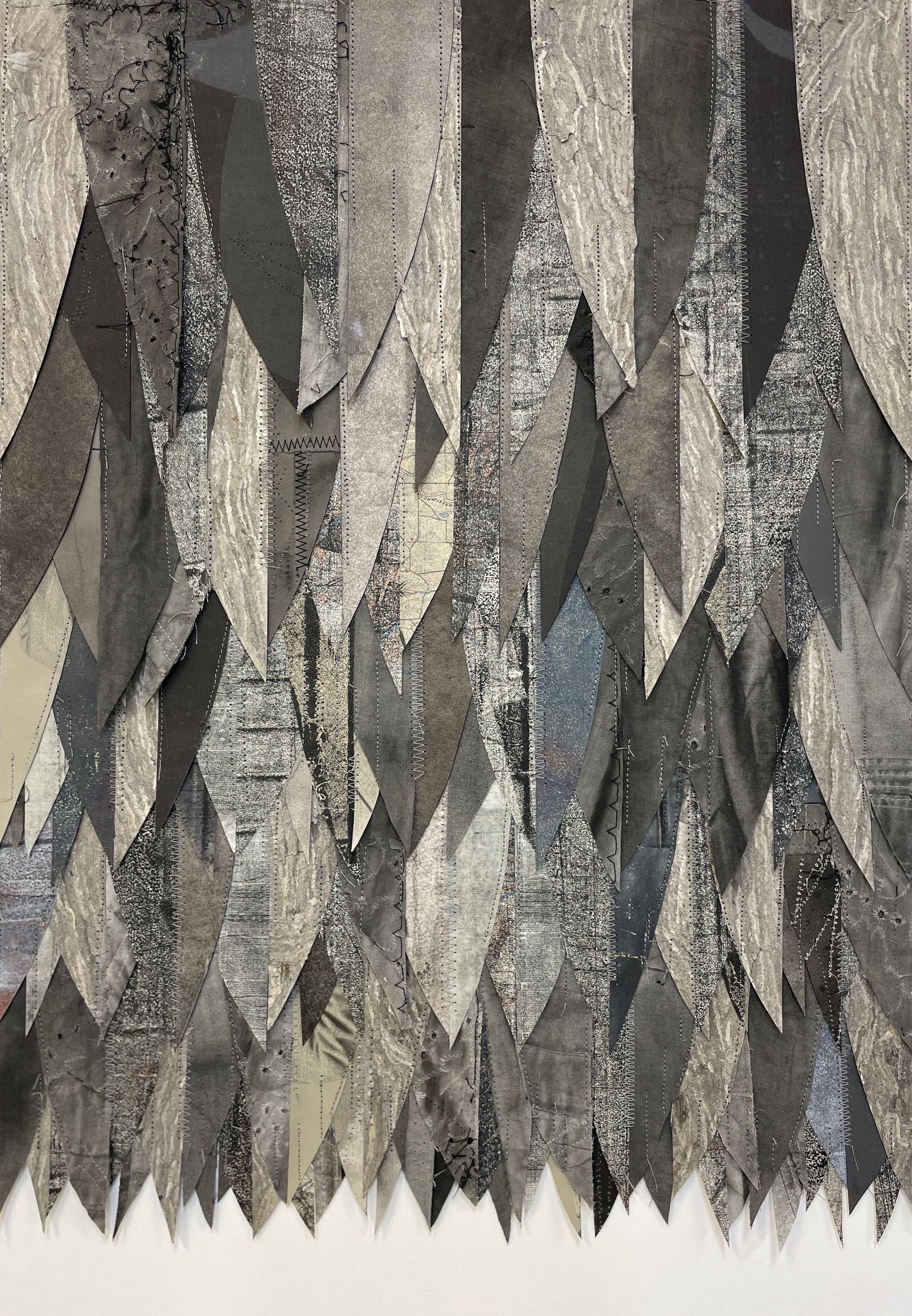 Abstract gray and beige geometric pattern with layered, jagged shapes resembling hanging crystals