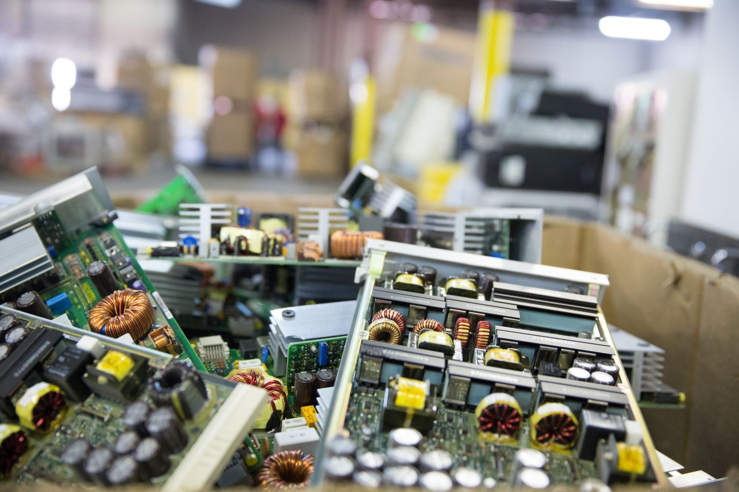 A pile of electronic components in a cardboard box in a warehouse.