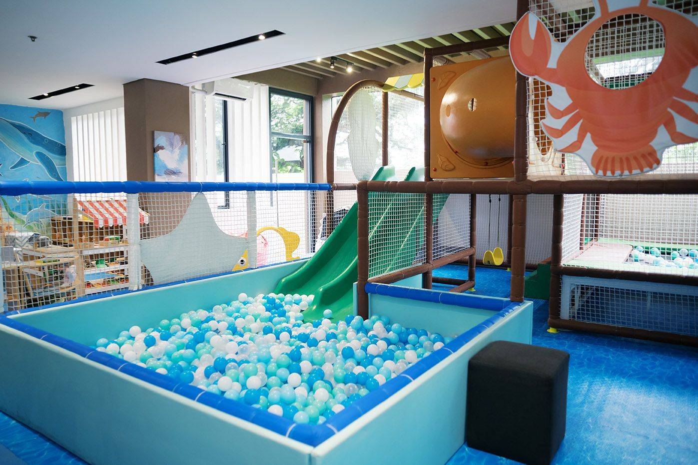 An indoor children’s play area in Hue Boracay in Station 2 with a ball pit, green slide, and a large orange crab cutout on a wooden structure.