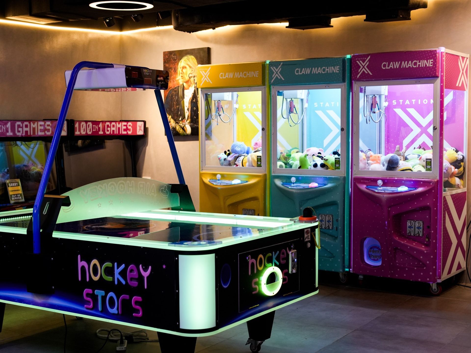 A group of air hockey tables and claw machines at Hue Hotel station X