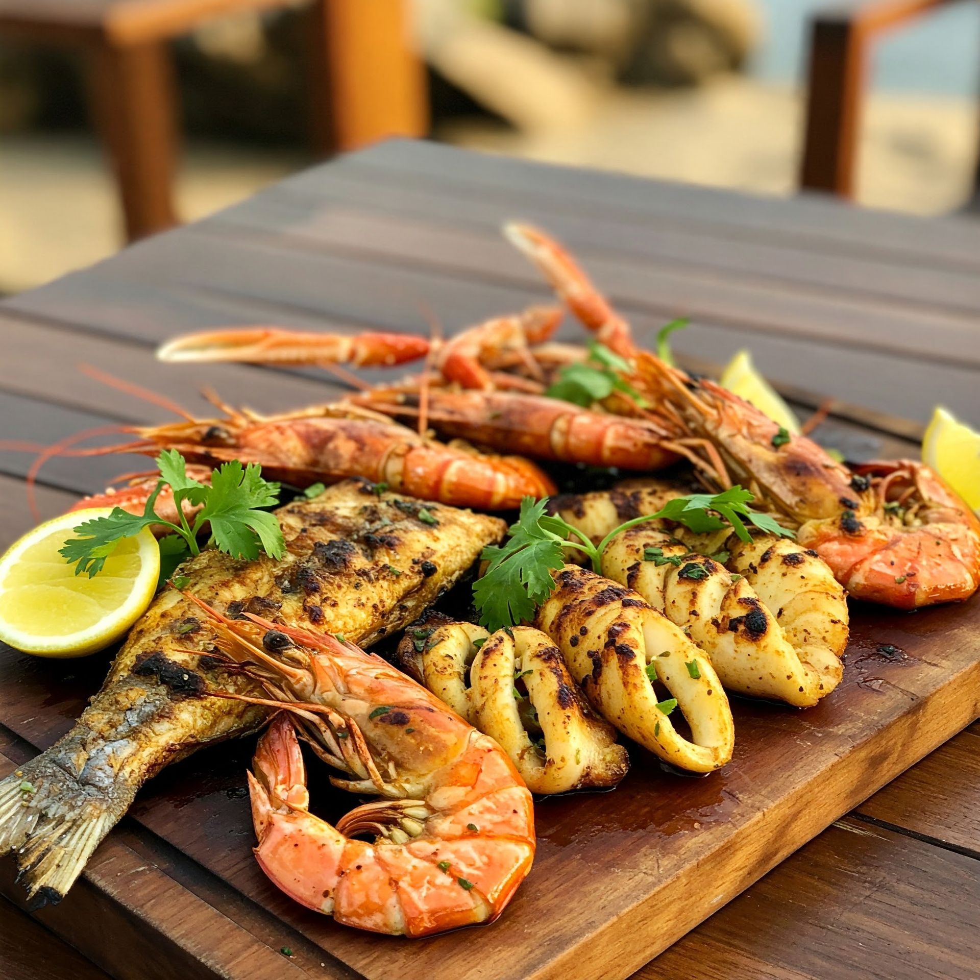 A wooden cutting board topped with shrimp and fish by La-ud restaurant
