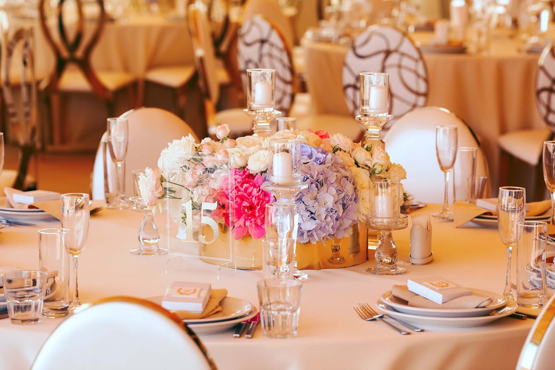 Elegant wedding reception table setting with centerpiece of flowers and candles.