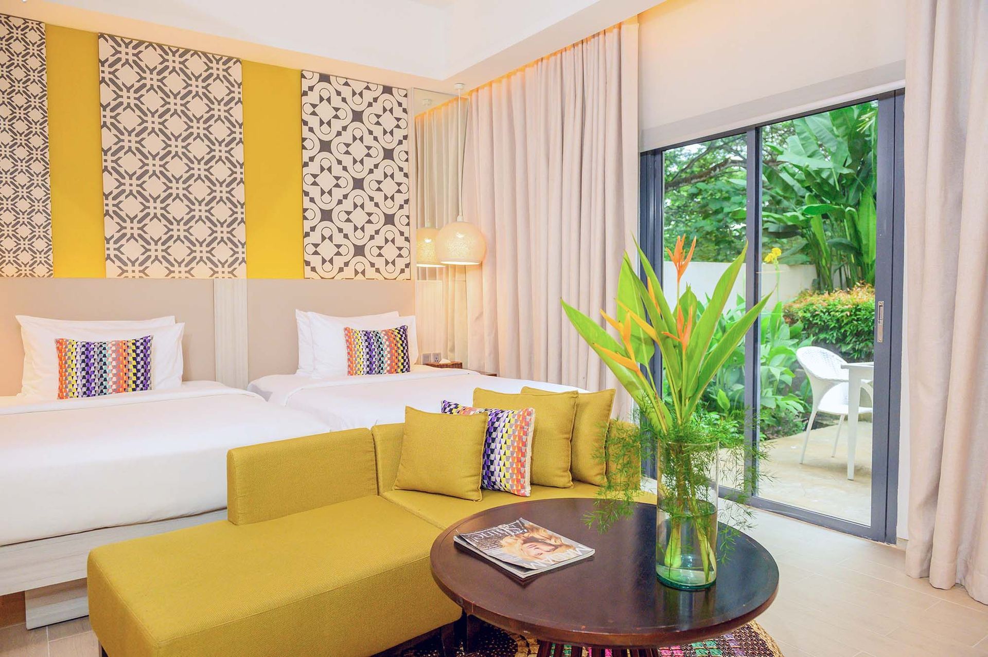 Woman rolling pink suitcase down a hotel hallway, smiling.