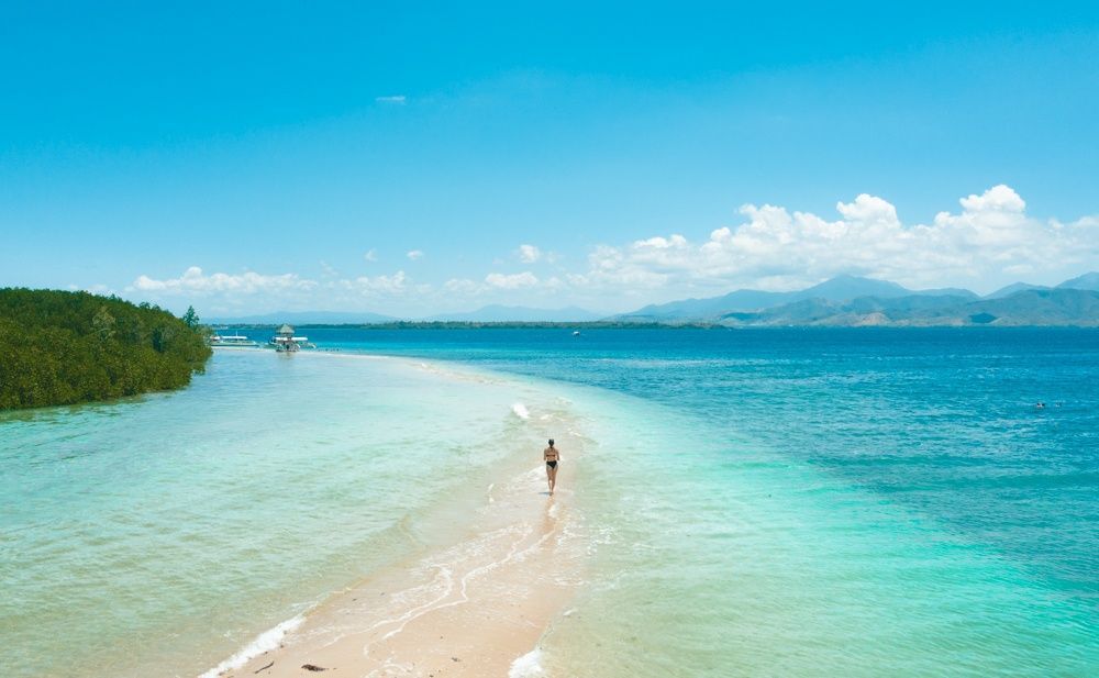 A person is walking on a sandy beach in Honda Bay Puerto Princesa