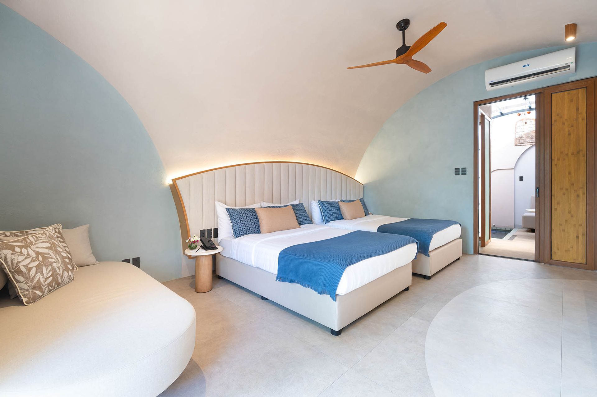 A woman is laying on a couch in a hotel room