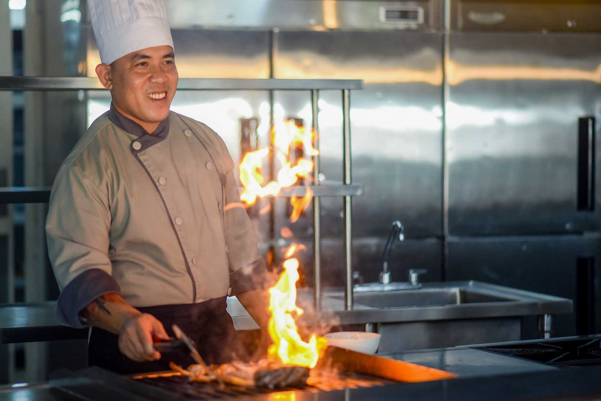 A chef is cooking food on a grill in a kitchen at LA-UD Restaurant