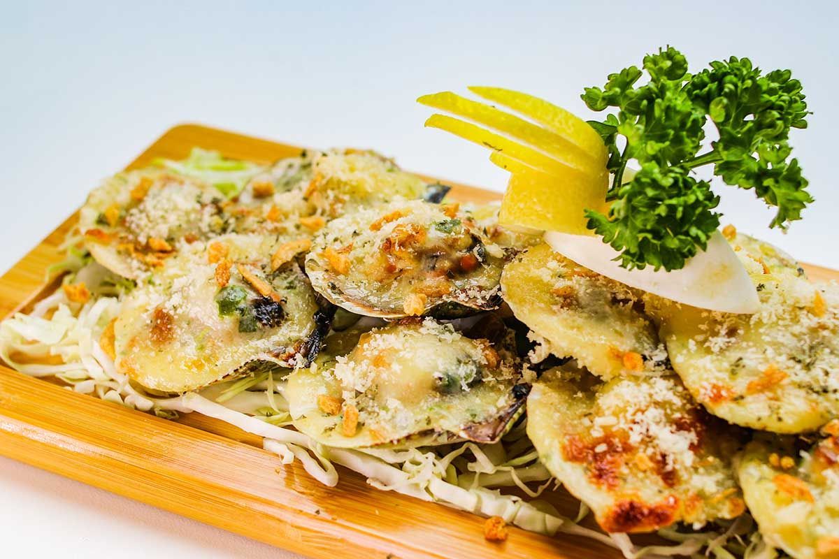 Breaded clams on wooden board, garnished with parsley and lemon slice.